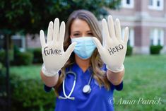 a woman wearing a face mask and gloves holds up her hands with the words future hero written on them