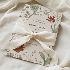 the wedding card is tied with a white ribbon and sits on top of a bed