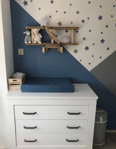 a baby's room painted in blue and white with stars on the wall behind it