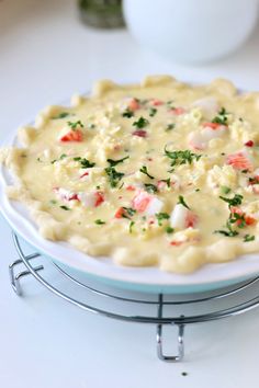 a white plate topped with a pie covered in cheese and veggie toppings