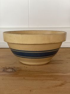 a white and blue bowl sitting on top of a wooden table next to a wall