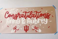 congratulations sign hanging on the wall with confetti around it and graduation caps in red