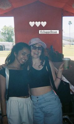 two women standing next to each other in front of a tent