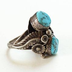 This is an Old Navajo Double Turquoise Ring Intricate Appliques Size 7.25 Sterling Silver C1970s. This size 7.25 Native American ring includes two polished turquoise stones (one with pyrite inclusions) surrounded by intricate twisted wire and appliques. The ring acid tests positive for sterling silver. The face measures 1 inch, and the ring weighs 9.1 grams. 2235635 More Native American Jewelry https://www.etsy.com/shop/redroselady?ref=hdr_shop_menu&section_id=15506102 More Southwestern Jewe Antique Turquoise Adjustable Rings, Vintage Blue Concho Ring, Vintage Blue Turquoise Ring For Anniversary, Vintage Handmade Turquoise Ring Collectible, Vintage Concho Ring Jewelry, Vintage Handmade Turquoise Ring, Handmade Vintage Turquoise Ring Collectible, Adjustable Vintage Turquoise Ring, Vintage Adjustable Concho Rings