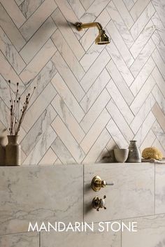 a bathroom with marble tile and gold faucets