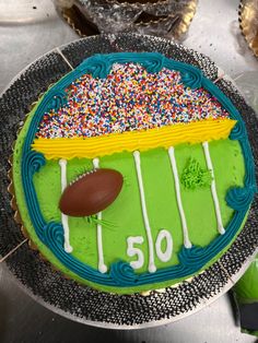 a football field cake with sprinkles and a football on the sideline