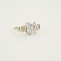 an oval and baguette cut diamond ring with three bagsuettes on each side