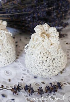 two crocheted bags sitting on top of a table next to some lavender flowers