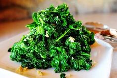 a pile of broccoli sitting on top of a white plate next to a spoon