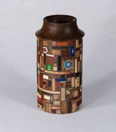 a wooden vase with many different colored designs on the outside and inside, sitting on a white surface