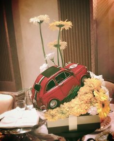 a red car sitting on top of a table filled with flowers