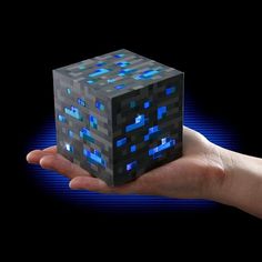 a hand holding a cube with blue lights on it's sides in front of a black background