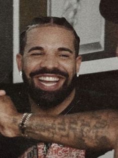 a man with tattoos on his arm smiling at the camera