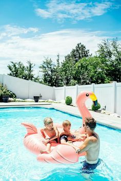 three people in an inflatable flamingo pool float with a child on it