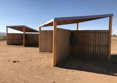 two wooden structures sitting in the middle of a dirt field