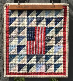 an american flag quilt hanging on the side of a building