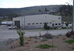 an empty parking lot in front of a building with cars parked on the side of it