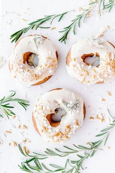 three doughnuts with icing and sprinkles on a white surface