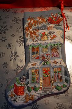 a cross stitch christmas stocking with santa's house and sleigh on it