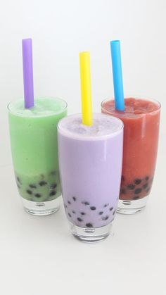 three different colored drinks with straws in them