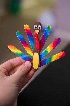 a hand holding a colorful paper turkey