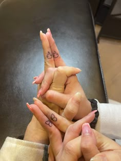 three people are holding their hands together with tattoos on their fingers and the other hand is pointing up