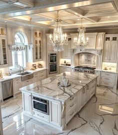 a large kitchen with marble counter tops and white cabinets, chandelier hanging from the ceiling