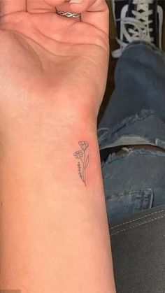 a woman's arm with a small flower tattoo on the left side of her wrist