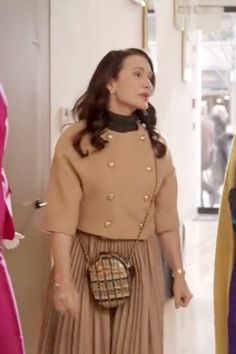 a woman in a brown dress is standing next to another woman wearing a pink and yellow outfit