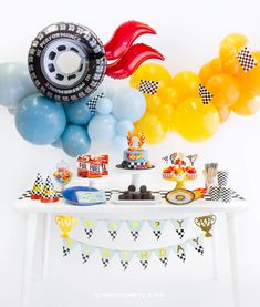 a table topped with lots of balloons and cake