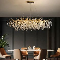 a chandelier hanging over a dining room table with beige chairs and a white table