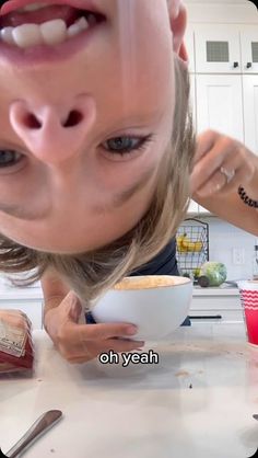 a woman is making a funny face while holding a bowl with food in front of her