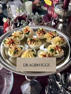 small deviled eggs on a silver platter with a sign that says dragon eggs