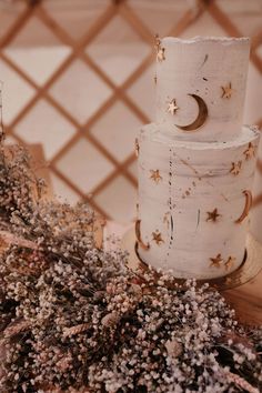 a three tiered cake sitting on top of a wooden table next to dried flowers