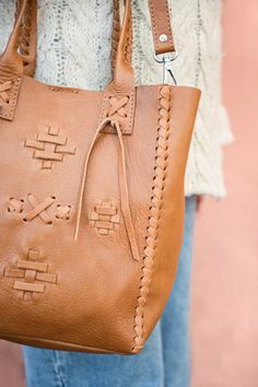 Carry your essentials in this handcrafted premium vegetable tanned leather bag, made by artisans in Buenos Aires. The unique braided design on the front with the drawing of the guarda pampa its a symbol of the southern region of Argentina associated with rural gaucho traditions. It’s the pefect accessory that goes with every outfit. • Vegetable tanned leather • Detachable shoulder strap • Interior pocket • A carabiner for your keys • Spacious main compartment • Snap closure • Unique braided deta Traditional Leather Bag With Woven Details, Traditional Woven Leather Bag, Artisan Leather Bags With Woven Detail, Artisan Woven Leather Bags, Leather Shoulder Bag With Braided Handles For Market, Handmade Leather Shoulder Bag For Market, Artisan Leather Shoulder Bag In Natural, Artisan Brown Shoulder Bag With Braided Handles, Artisan Leather Bags With Braided Handles