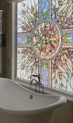 a bath tub sitting under a large stained glass window