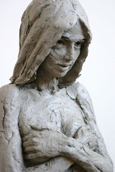 a sculpture of a woman with her hands on her chest, wearing a hoodie