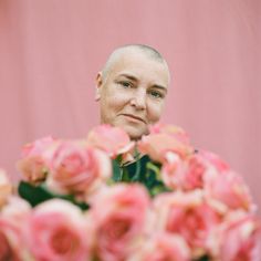 a man is looking at the camera with roses in front of him and behind him