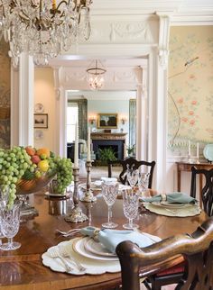 the dining room table is set with plates, glasses and fruit on top of it