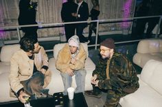 three men sitting on a couch with drinks in their hands