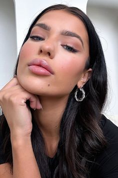 a woman with long black hair and earrings on her head is posing for the camera