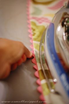 a person's hand is on the edge of a piece of cloth next to a sewing machine