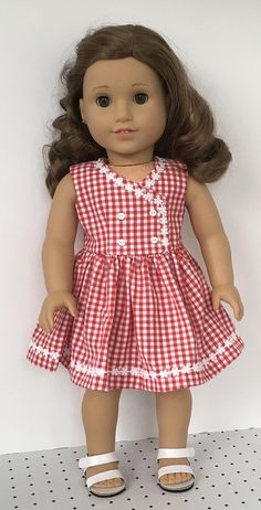 a doll with brown hair wearing a red and white checkered dress on a shelf