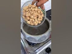 a person holding a bowl full of food on top of a stove with the lid down