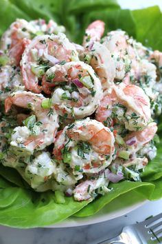 a salad with shrimp in it on top of some lettuce and garnish