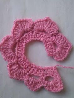 a crocheted pink object is laying on the table next to it's string