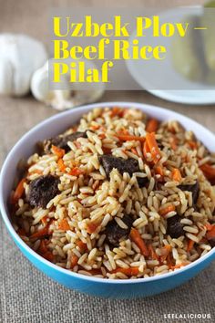 a bowl filled with rice, carrots and mushrooms next to garlic on a table