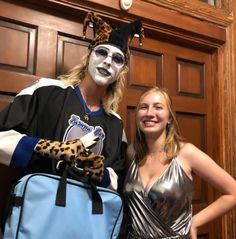 two people in costumes standing next to each other with a bag on their shoulders and one person wearing a mask