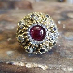 This Victorian Ruby Ring Made Of 2 Tones . Top Yellow 18k Yellow Gold Alloy With A Semiprecious Cabochon Ruby And Faceted 8 Smokey Topaz Set All Around The The Top. The Body Or Band Is Made Of Sterling Silver , Weights 16.7 Grams , Made By Hand With The Best Material And Love ! Bwood ,Metal Box Included !!! Luxury Multi-stone Ruby Ring, Exquisite Multi-stone Yellow Gold Ruby Ring, Luxury Ruby Ring With Multi-stone Round Cut, Heirloom Gemstone Dome Ring For Formal Occasions, Luxury Multi-stone Round Cut Ruby Ring, Ceremonial Diamond Fine Jewelry, Multi-stone Diamond Jewelry With Round Stones, Luxury Ceremonial Gemstone Jewelry, Elegant Domed Ruby Ring