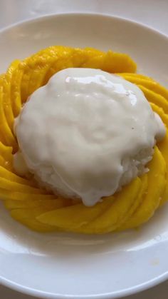 a white plate topped with an ice cream and mango slice covered in icing on top of it